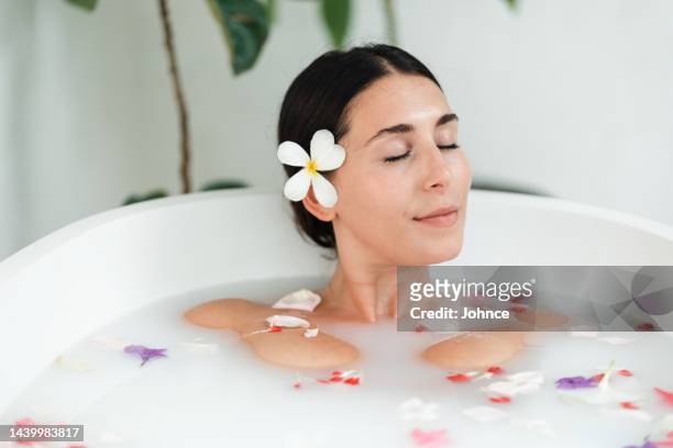 schöne frau, die luxuriöse spa-momente genießt - milchbad stock-fotos und bilder