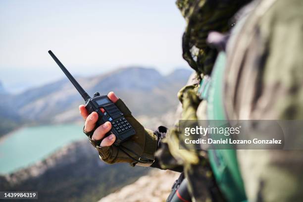 stock photo. detail of military person holding a walkie talkie radio phone in mountain - military photos et images de collection
