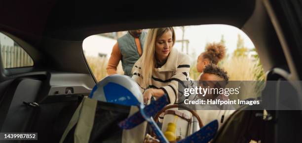 cheerful family preparing for holiday, putting their stuff in car trunk. - large family photos et images de collection