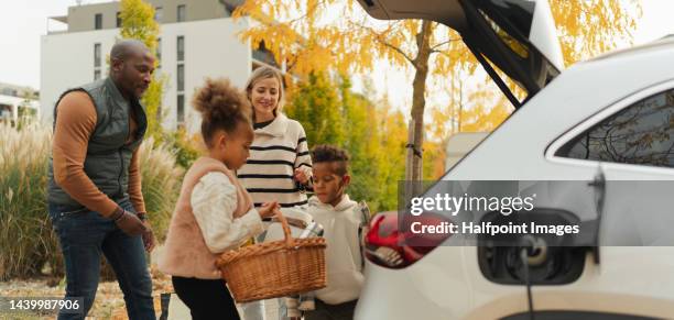 cheerful family preparing for picnic during their car charging. - public transport stock-fotos und bilder