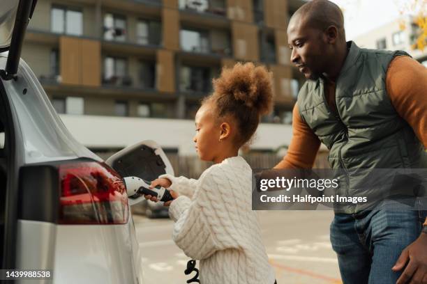 close-up of father with his daughter charging their electric car. - elektroauto mensch stock-fotos und bilder