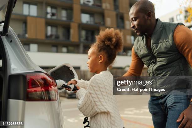 close-up of father with his daughter charging their electric car. - elektrische auto stockfoto's en -beelden