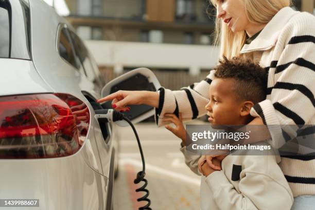 close-up of mother with her son charging their electric car. - hybrid car stockfoto's en -beelden