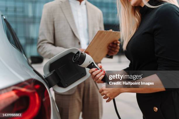 young salesman showing charging electric car. - electric car display stock pictures, royalty-free photos & images