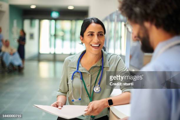 happy hospital doctor chatting to colleague - family doctor stockfoto's en -beelden