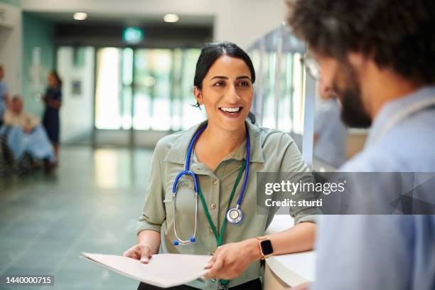 happy hospital doctor chatting to colleague - médico de clínica geral imagens e fotografias de stock