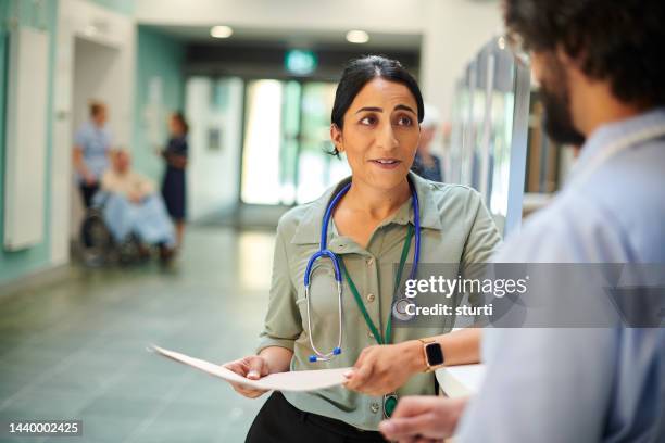 hospital doctor chatting to colleague - busy hospital lobby stockfoto's en -beelden