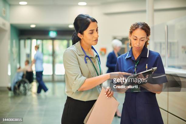 hospital colleagues checking medical records database - administrative professionals stockfoto's en -beelden