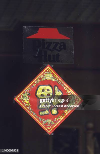 View of a sign for Good Luck under a Pizza Hut logo in Beijing, China, January 1994.