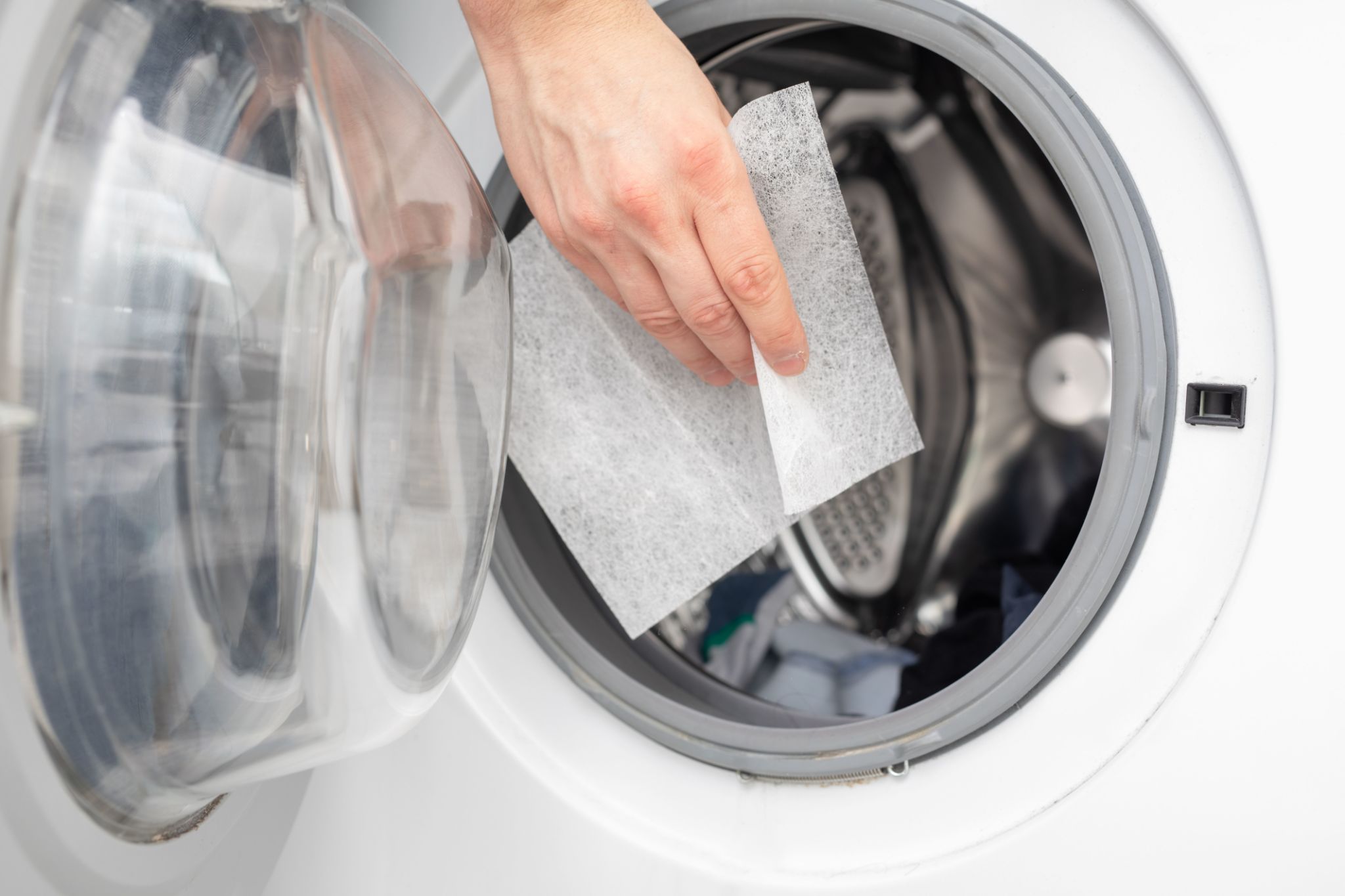 Hand dropping dryer aromatic sheets in a washing machine Hand dropping dryer aromatic sheets in a washing machine