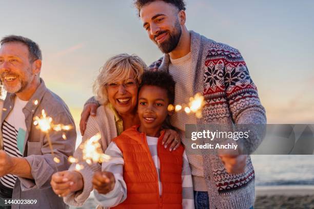 multi-generation family celebrating christmas on the beach - sparklers stock pictures, royalty-free photos & images