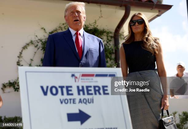 Former U.S. President Donald Trump stands with former first lady Melania Trump as he speaks to the media after voting at a polling station setup in...