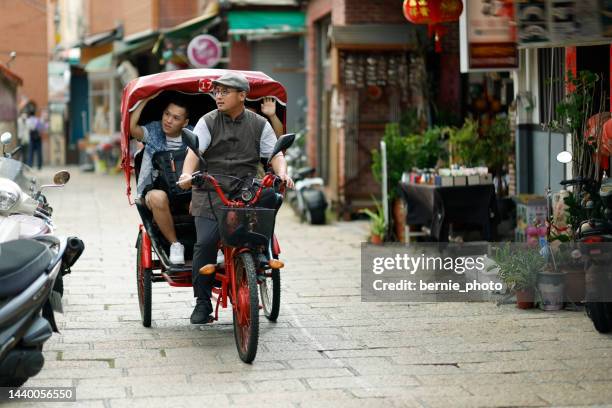 two men on a tricycle ride around changhua's lukang street - taiwanese ethnicity stockfoto's en -beelden