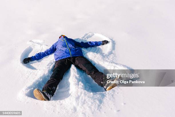 man has fun making a snow angel - snow angel 個照片及圖片檔