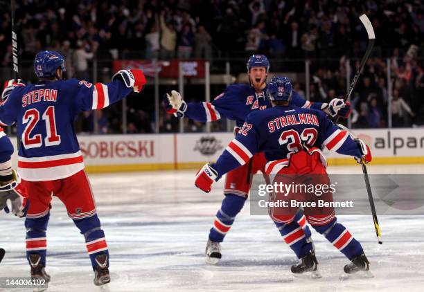 Marc Staal of the New York Rangers celebrates with teammates Anton Stralman and Derek Stepan after scoring the winning a goal in overtime against...