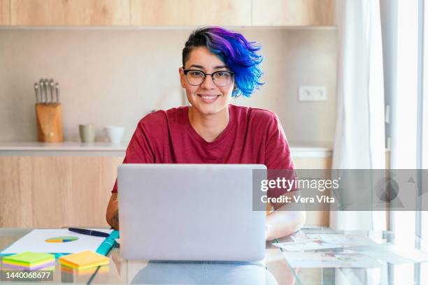 hispanic young lesbian woman with red shirt working on computer at kitchen - red dress shirt stock pictures, royalty-free photos & images