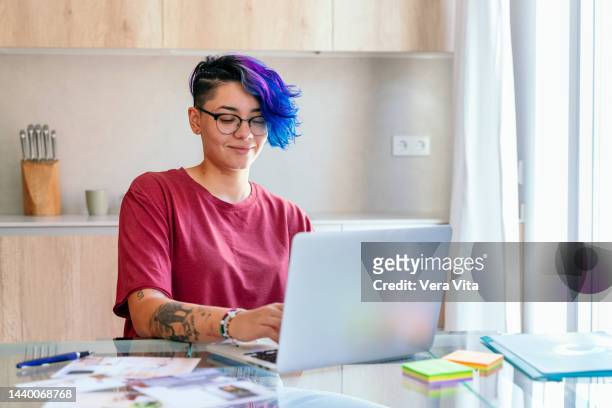 lesbian woman with blue short hair working with computer and creativity design at home - dyed red hair fotografías e imágenes de stock