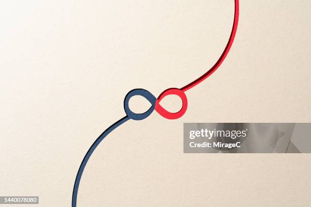 paper cut of a connected infinity symbol with blue and red colors - consolidation stock pictures, royalty-free photos & images