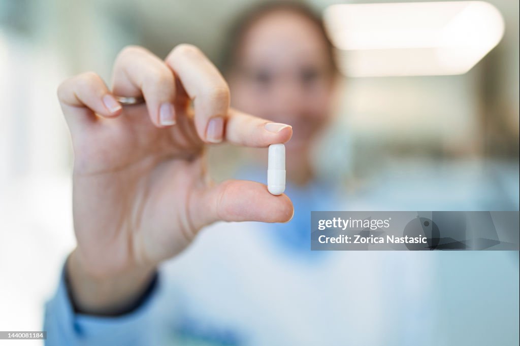 Doctor holding a capsule pill in hand in laboratory