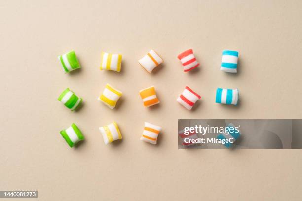 multi colored candies organized on beige background - spoil system stock pictures, royalty-free photos & images