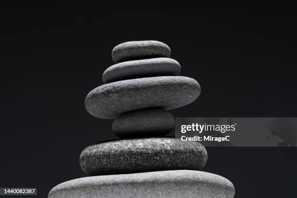 balanced grey pebbles stacking on black background - steine balance stock-fotos und bilder