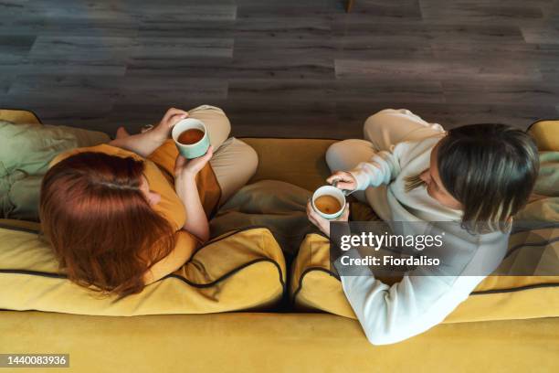 two women are sitting and talking - mother daughter couch imagens e fotografias de stock
