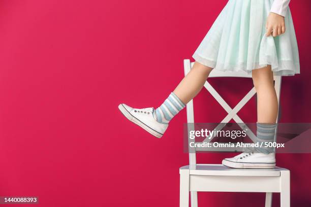 little girl standing on chair against color background - female foot models stock-fotos und bilder