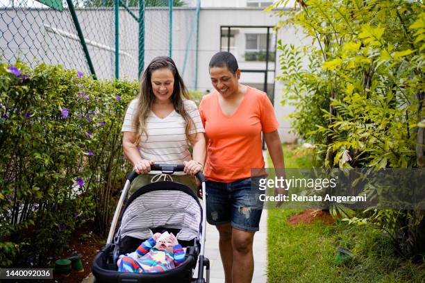 lesbian couple walking with baby in stroller - prams stock pictures, royalty-free photos & images