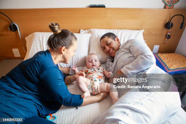 lesbian couple taking care of baby in bed - cute lesbian couples stockfoto's en -beelden