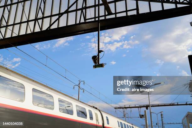 train passing along the tracks seen from a low angle to the clear sky, with a lamp hanging in the background - french provincial interior stock-fotos und bilder