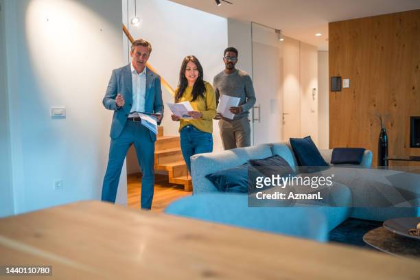 mature caucasian salesman and real estate agent selling a beautiful and modern house to a young couple - house showing stock pictures, royalty-free photos & images