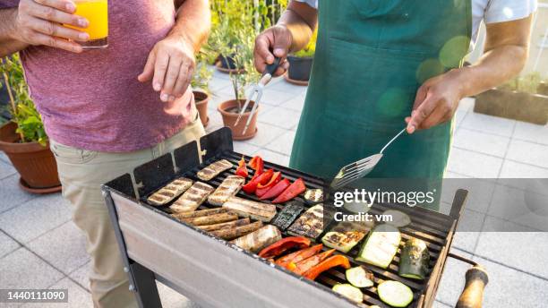 zwei freunde bereiten fleischersatz und gemüse auf grill zu - fleischersatz stock-fotos und bilder