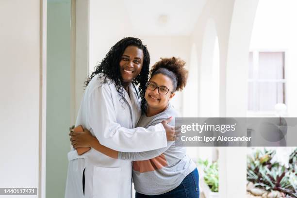 dottore trans che abbraccia un paziente in clinica - transgender foto e immagini stock