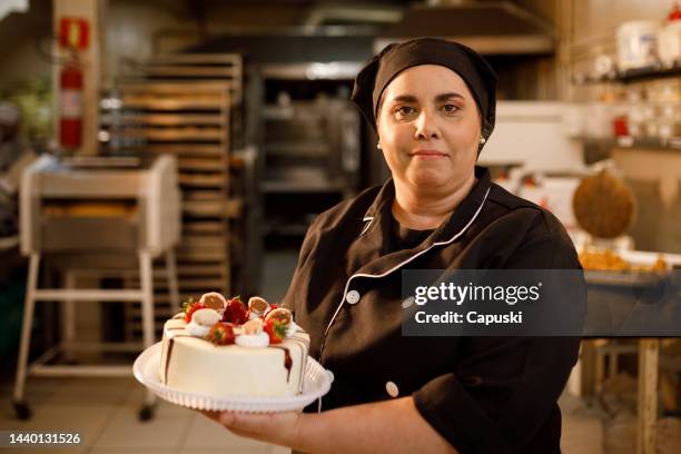 chef pastelero mostrando un pastel de chocolate y fresa - pasteleros fotografías e imágenes de stock