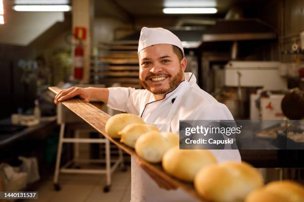 smiling baker with freshly baked bread - bakery imagens e fotografias de stock