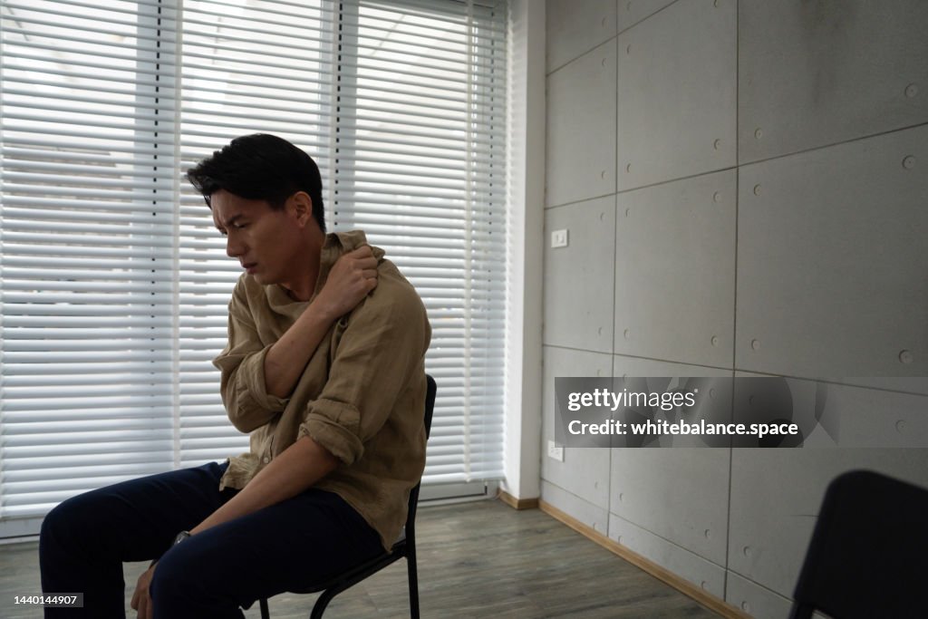 Asian man having a breakdown during group therapy session about addiction.