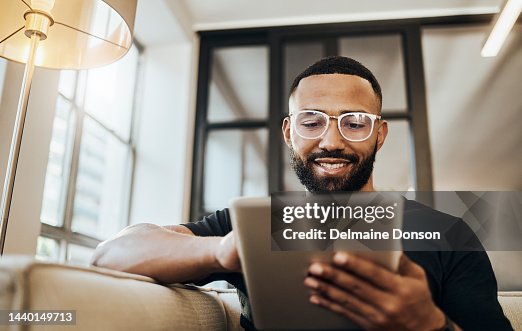 Black man, tablet and smile for social media post, shopping online or browsing internet creative content at home. Young africa american happy, relax and calm on tech digital app on device Black man, tablet and smile for social media post, shopping online or browsing internet creative content at home. Young africa american happy, relax and calm on tech digital app on device