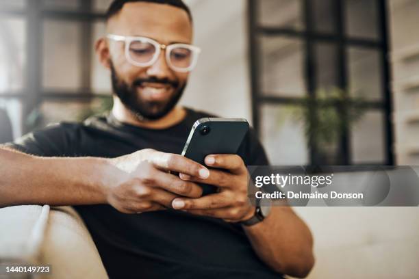 glücklicher mann, social-media-telefon und wohnzimmer entspannen, smartphone und online-kommunikation tippen, benachrichtigung lesen und web auf dem sofa. smile guy hände, mobile verbindung und heimnetzwerktechnologie - man using phone stock-fotos und bilder