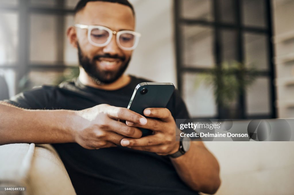Happy man, social media phone and living room relax, typing smartphone and online communication, reading notification and web on sofa. Smile guy hands, mobile connection and home network technology