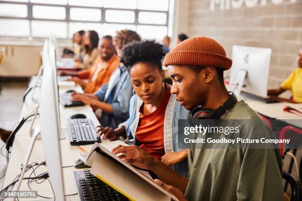 two college students reading a textbook during computer class - high tech campus stock pictures, royalty-free photos & images