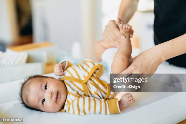 cropped shot of young asian mother taking care and changing the diaper for her baby at home. new life. love, care and tenderness - changing diaper ストックフォトと画像