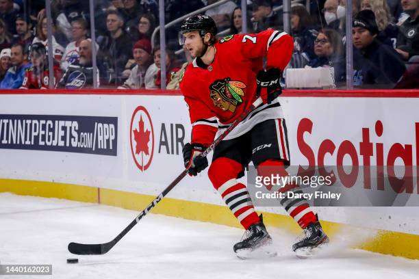 Alec Regula of the Chicago Blackhawks plays the puck behind the net during first period action against the Winnipeg Jets at the Canada Life Centre on...