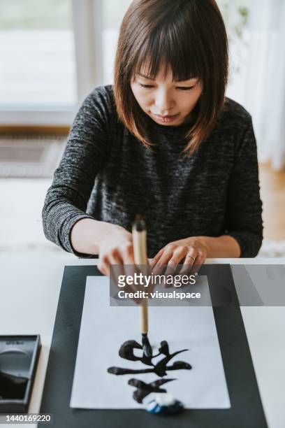 japanese woman writing traditional new year's calligraphy - non western script stock pictures, royalty-free photos & images