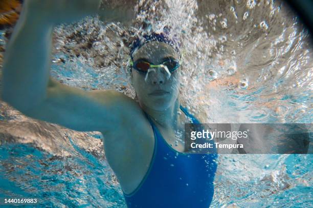 close-up of strong young woman making a bubbly splash during freestyle swim training - swimming free style pool stock pictures, royalty-free photos & images
