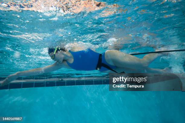 young determined female training freestyle with a resistance swim belt in swimming pool - woman swimmer freestyle stock pictures, royalty-free photos & images