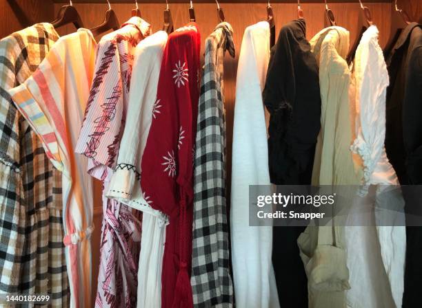 close-up of women's clothes hanging in an illuminated wardrobe - hanging blouse stock pictures, royalty-free photos & images