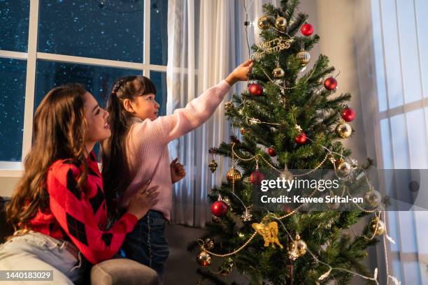caucasian mother and kid daughter decorating christmas tree in house. young little daughter feeling happy and excited to celebrate holiday christmas thanksgiving party together with parents in house. - happy santa claus over white blank stockfoto's en -beelden