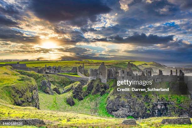 rocky coastline with dunluce castle, county antrim, northern ireland, uk - dunluce castle stockfoto's en -beelden