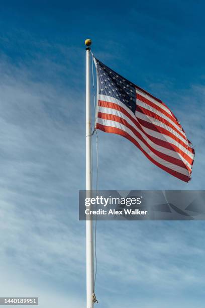 american flag flying against blue sky - fahnenstange stock-fotos und bilder