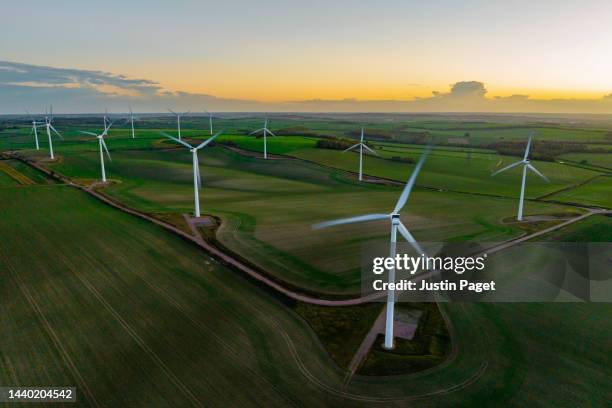 drone view of a wind farm at sunset with multiple wind turbines - wind power stock pictures, royalty-free photos & images